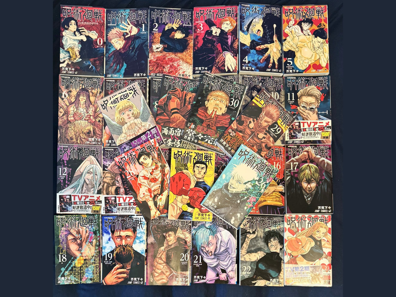 All 31 covers of the Jujutsu Kaisen Japanese manga set laid out together, volume 0 through volume 30, several still wearing their anime obi bands