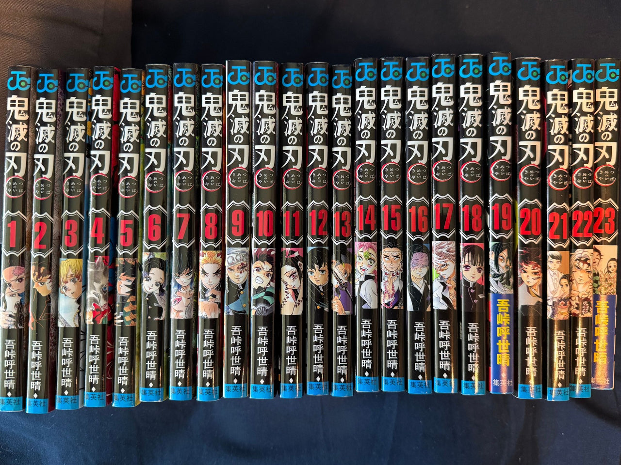 All 23 spines of the Demon Slayer Japanese manga set lined up in order, volumes 1 through 23, Jump Comics editions