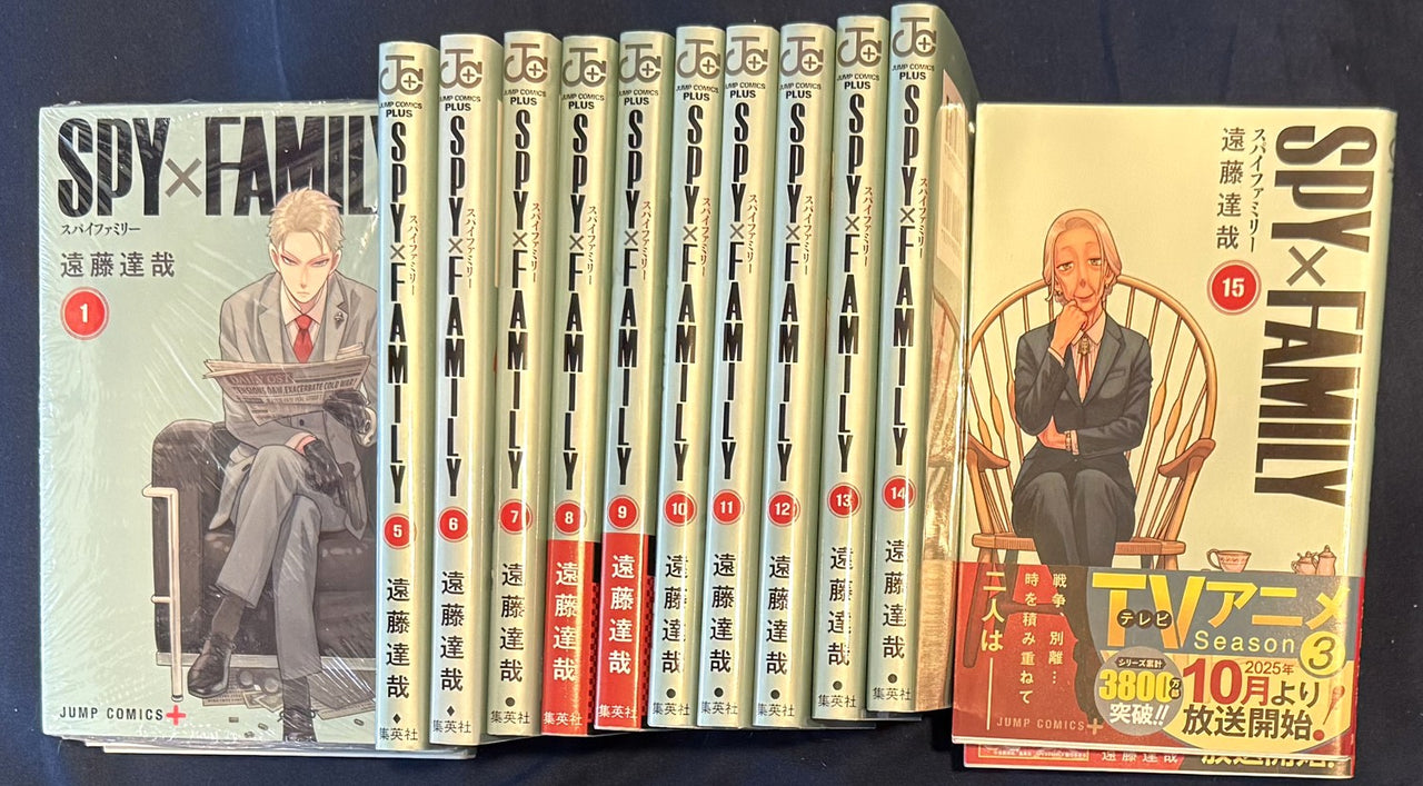 SPY x FAMILY volume 1 and volume 15 covers beside the numbered spines, volume 15 still wearing its original obi band